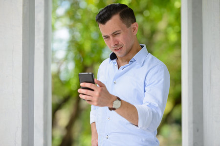 Young handsome businessman using phone at the park