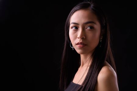 Face of young beautiful Asian woman looking backの写真素材