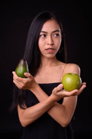 Portrait of young Asian woman thinking with apple and avocadoの写真素材