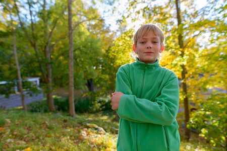 Young handsome boy with arms crossed at the park in autumnの写真素材