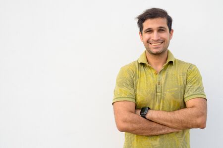 Portrait of happy young Persian man smiling with arms crossedの写真素材