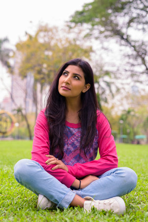 Young beautiful Persian woman thinking at the park