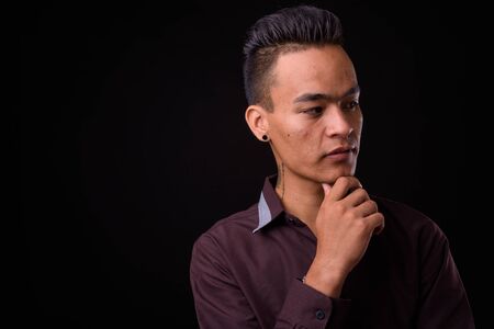 Portrait of young handsome Indian businessman thinkingの写真素材