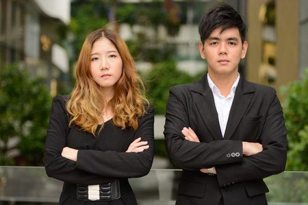 Young Asian business couple with arms crossed together at the parkの写真素材