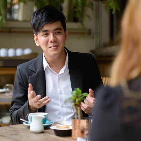 Young Asian business couple talking together at the coffee shopの写真素材