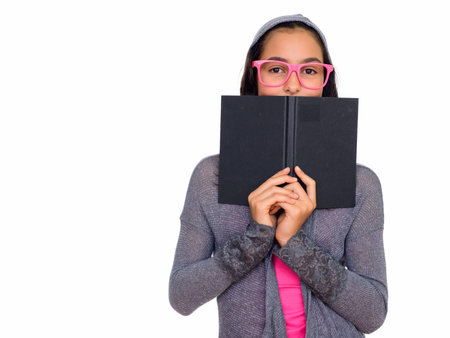 Studio shot of young beautiful teenage girl hiding behind book isolated against white background