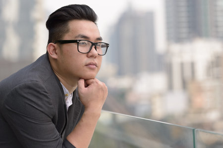 Young overweight Asian businessman with eyeglasses thinking