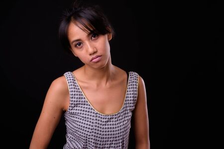 Young beautiful Asian woman against black backgroundの写真素材