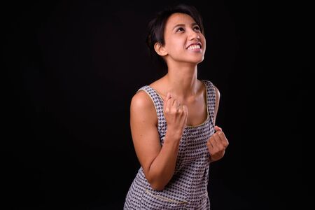 Young beautiful Asian woman against black backgroundの写真素材