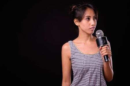 Young beautiful Asian woman against black backgroundの写真素材