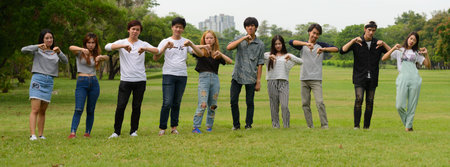 Group of young Asian friends hanging out and relaxing together at the park outdoors