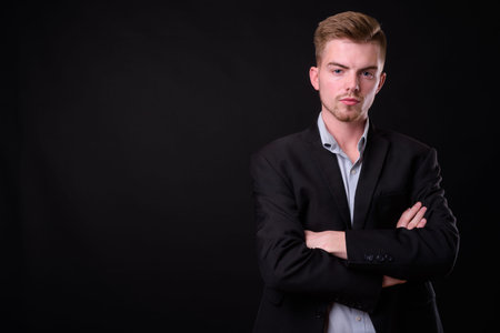 Portrait of young handsome blond bearded businessman in suit