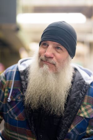 Face of mature bearded hipster man thinking in the city streetsの写真素材