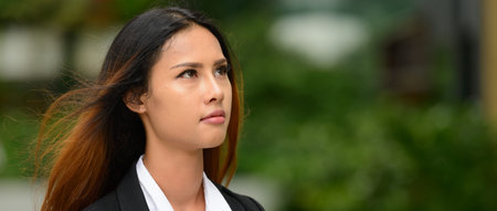 Young beautiful Asian businesswoman thinking in the parkの写真素材