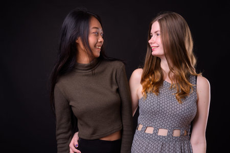 Two happy multi ethnic young beautiful women smiling together