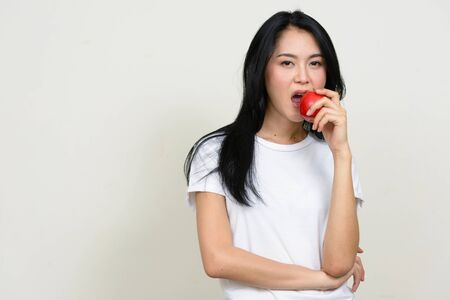 Portrait of young beautiful Asian woman eating appleの写真素材
