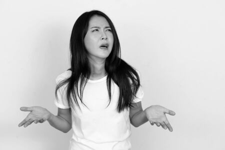 Stressed young Asian woman shrugging shoulders and looking confusedの写真素材