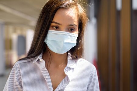 Face of stressed young Asian tourist woman with mask thinking at the airportの写真素材