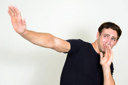 Portrait of stressed young man looking scared with arms raised