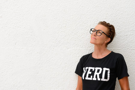 Mature nerd woman wearing big eyeglasses and standing against white background outdoors while...