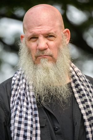 Mature bald hipster man with long beard at the park outdoors