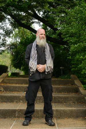 Mature bald hipster man with long beard at the park outdoors