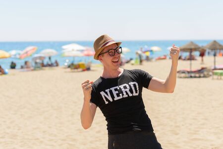 Portrait of young handsome tourist man as nerd at the beach in Spainの写真素材
