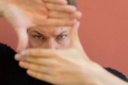 Face of young handsome man focusing with finger frame gestureの写真素材