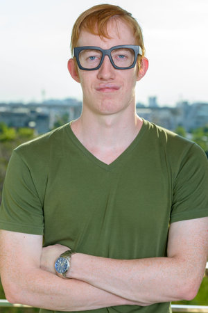 Nerd man with red hair wearing eyeglasses against view of the cityの写真素材