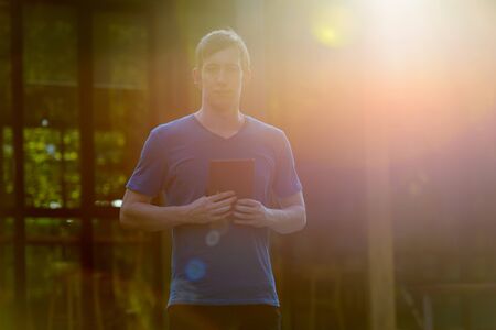 Portrait of man with red hair holding book outdoorsの写真素材