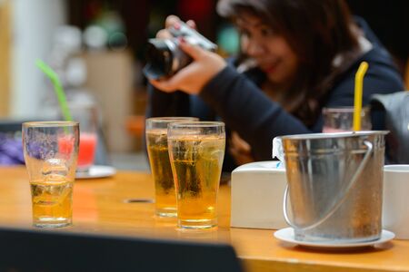 Happy young overweight Asian woman taking picture with beer on tableの写真素材
