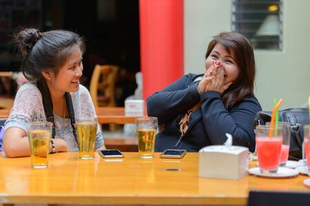 Happy young Asian women as friends hanging out and drinking beer outdoorsの写真素材