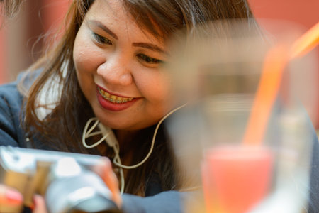 Happy young overweight Asian woman smiling at the coffee shop
