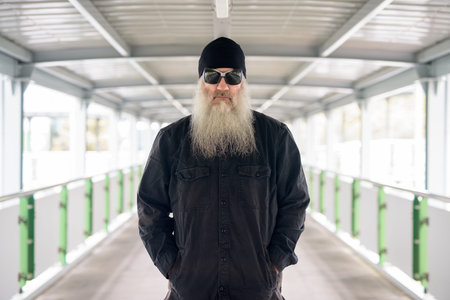 Mature bearded man wearing sunglasses at footbridge in the city