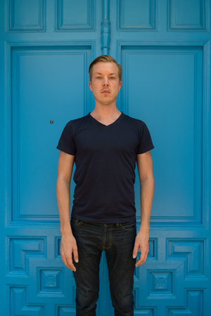 Young handsome man standing in front of blue door
