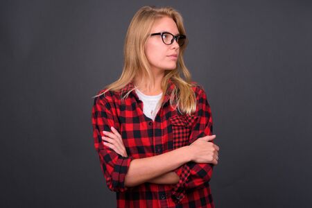 Portrait of young blond hipster woman thinking with arms crossedの写真素材