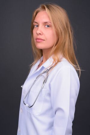 Profile view of young blond woman doctor looking at cameraの写真素材