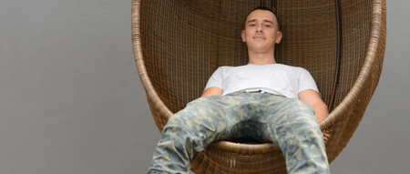 Handsome man sitting on wicker chair outdoors