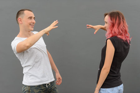 Portrait of happy couple doing handshake together against gray wall