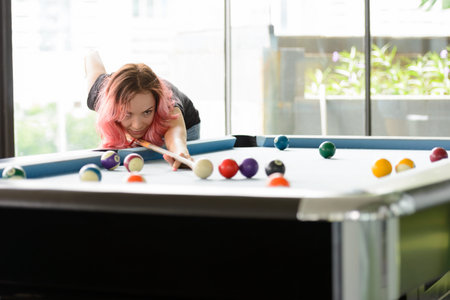 Beautiful woman with pink hair playing billiard