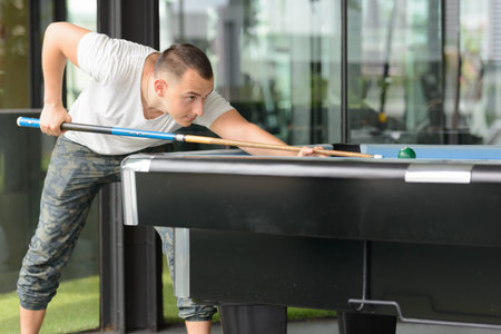 Handsome man leaning on pool table while playing billiard
