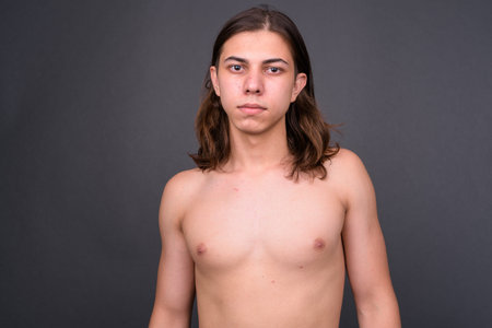 Young handsome androgynous man with long hair shirtless