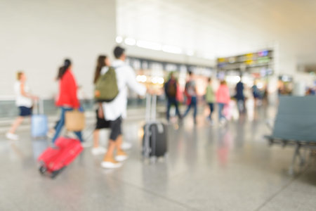 Defocused terminal departure check in at airport with walking travelers
