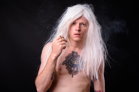 Punk rocker man wearing wig against black background