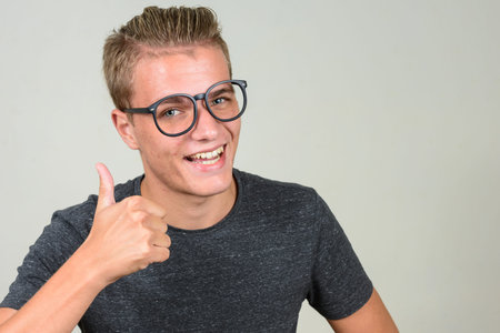 Happy young blond nerd man with eyeglasses giving thumbs up