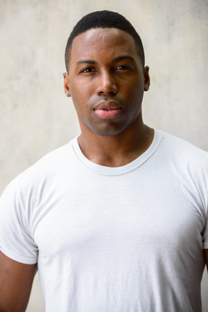 Face of young handsome African man against concrete wall