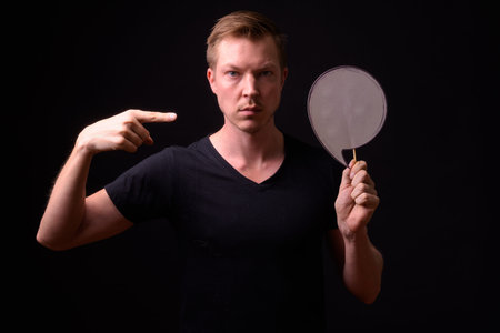 Portrait of young handsome man holding and pointing at paper sign