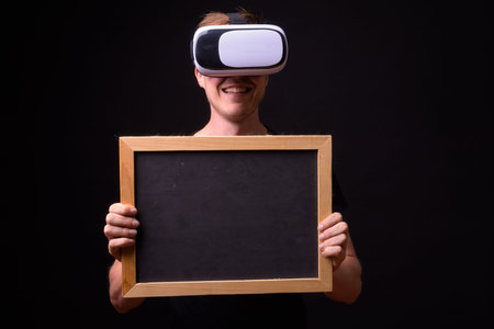 Portrait of happy young man using virtual reality headset and holding blackboard