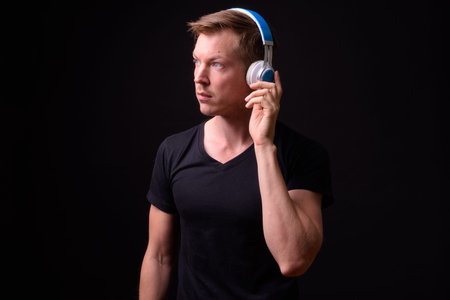Portrait of young handsome man thinking and listening to music