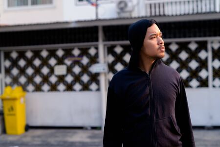 Young Asian man with hoodie thinking in the streets outdoorsの写真素材